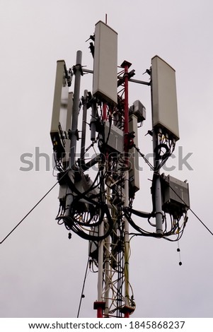 Close-up of tower with 5G and 4G cellular network antenna on grey cloudy sky background.
