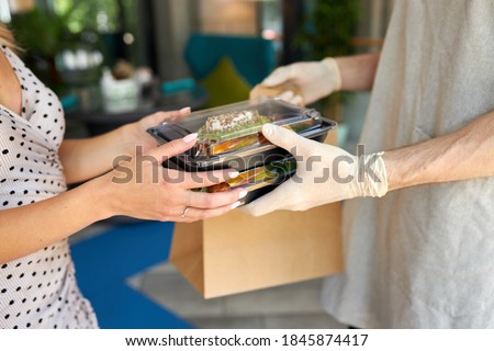 cropped female client make order in restaurant and take it by waiter in protective gloves. give away orders, food in containers. close-up Royalty-Free Stock Photo #1845874417