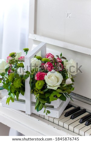 White wooden box with bouquet white and pink roses and chrysanthemums on white piano. Decoration of home. Flowers boxes. Wedding decoration