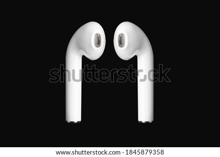 White Apple AirPods photographed on a black background