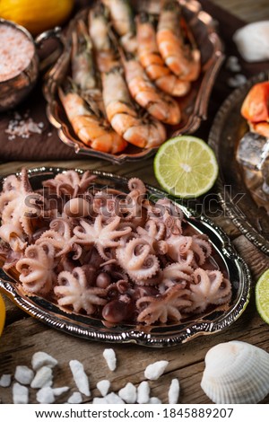 Close-up top view of assorted seafood served with lime on rustic wooden background, lemon and seashells. Healthy food. King dinner.