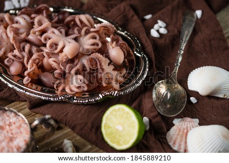 Close-up view of baby octopuses served with lime and seashells on brown napkin background. Concept of delicious meal from the sea. Healthy food. Traditional islands dish.