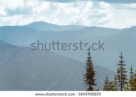 Scenic view of misty mountain valley. Gentle hills under overcast clouds.