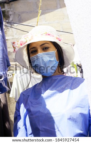 Young woman with hygienic facial surgical mask and her panoramic preventive team of medical staff with her payero hat in the background of the house.