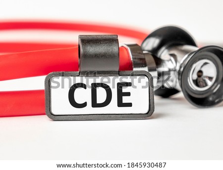 CDE Complete dental oral evaluation lettering on a business card with a holder, next to the red stethoscope. Medical concept. Treatment and prevention. Human health.