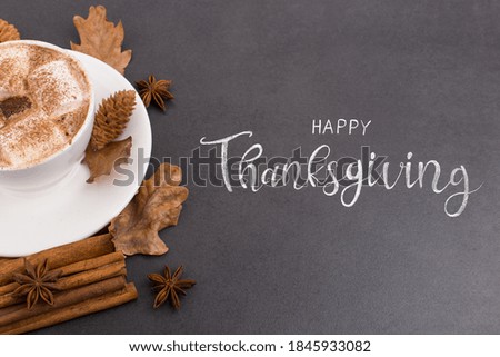 Thanksgiving greetings. Aromatic drink, coffee with marshmallows and spices, leaves on stone background, top view. Kaligraphic capital inscription.