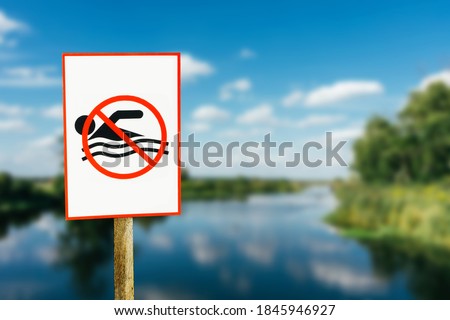 No swimming sign. Entering water is forbidden. Safety lake shore restrictions. Shallow water danger background. Small forest fishing pond. Dangerous river swimming accident. Strong river current.