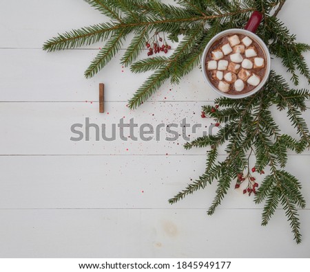 pine branches and mug of hot chocolate on rustic white board background, clothespin for picture attatchment 