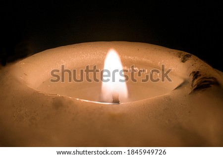 Candle light with fire from wick, in the night, close up or macro photography