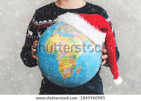 Merry Christmas. kid holding earth globe with a Santa hat with snowflakes