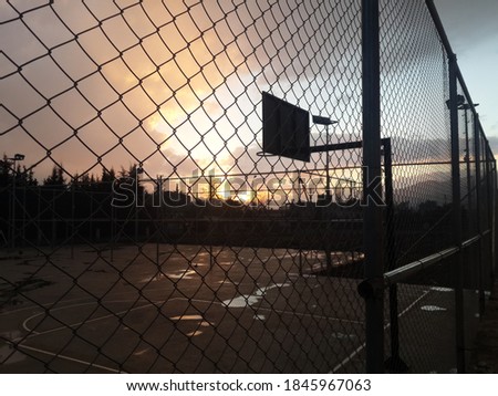 basketball hoop behind wires in the sunset