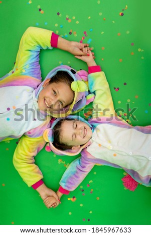 two girls in bright costumes on a green background with confetti. The concept of a holiday, Birthday and sales