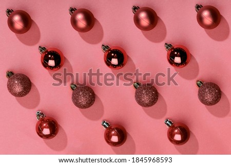 Red Christmas baubles decoration on red background with copy space. New Year greeting card. Minimal style. Flat lay. Pattern.