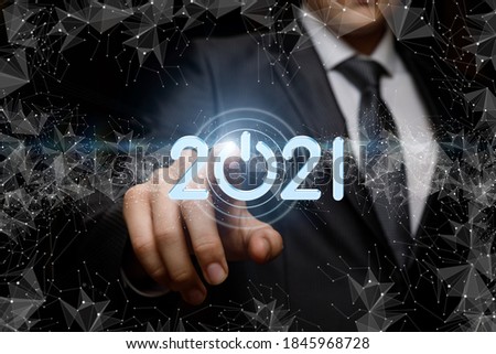 Businessman clicks on numbers 2021 on a dark background.