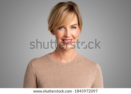 Portrait shot of beautiful blond woman looking at camera and smiling while standing at isolated grey background. Royalty-Free Stock Photo #1845972097
