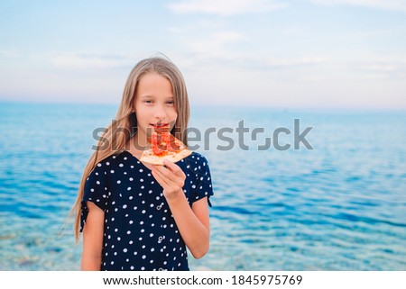 Girl relaxing on the beach with a slice of pizza in her hand