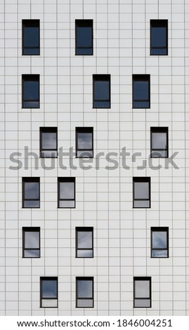 Urban abstract picture. Part of the facade of a building in a modern style with an asymmetrical arrangement of windows. Abstract building texture with modern creative design, vertical shot