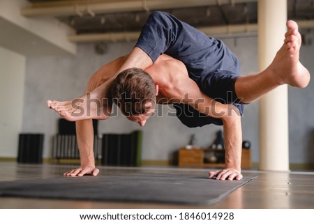 Strong male yogi standing on his hands with both feet in the air indoors Royalty-Free Stock Photo #1846014928