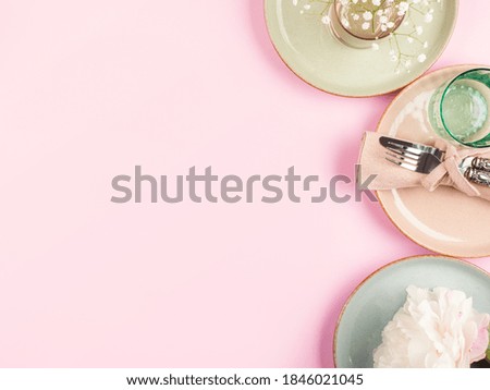 Pastel color ceramic and glass tableware with floral decor on pink background. Flat lay with modern dishes and crockery. Copy space