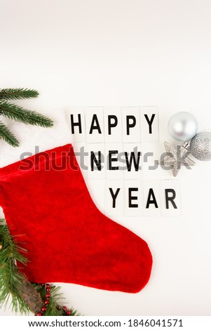 Santa's red stocking on a white background together with a toy in the form of a star and a ball. Happy new year lettering