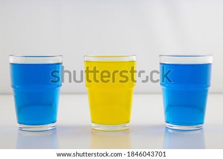 Glasses with liquid in colors representing flag of Sweden. Perfect picture for a quiz.
