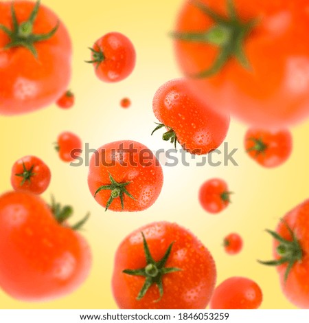 Many red tomatoes free falling on gradient yellow background. Selective focus - shallow depth of field.