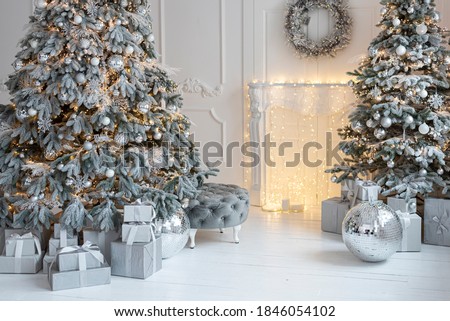 White decorated christmas room with two christmas trees, chimney, a lot of presents in country house