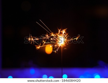 Sparks and fire on a black and blue background. Festive Merry Christmas sparklers. Golden Magic lights for holiday poster, birthday or party concept.