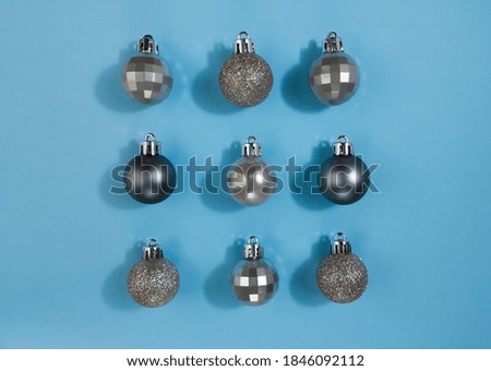 Metallic color Christmas balls on a blue pastel paper. Festive symmetry flat lay.