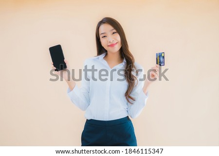 Portrait beautiful young business asian woman with phone and credit card on color isolated background