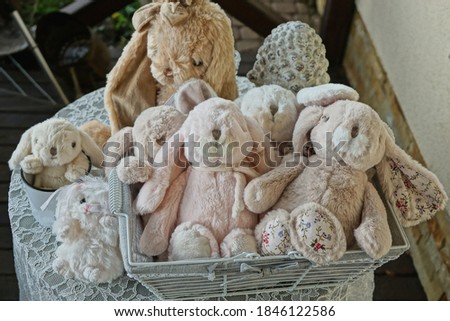 a bunch of soft plush toys pink and gray hares in a box on a white table