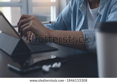 Close up of  business woman, graphic designer using stylus pen touching on digital tablet screen, typing on keyboard. Casual businesswoman online working at home with mobile phone on office table