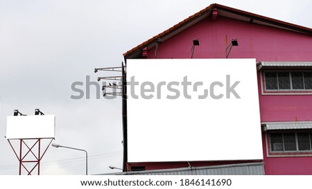 A blank billboard on a pink building wall. White cloth square information board on outdoor metal posts. On a blue sky background with a copy space. Selective focus