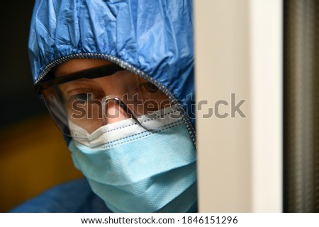 Tired doctor, medical worker wearing a protective suit, goggles and a surgical mask. Health care staff, nurse, high quality medical care, coronavirus concept.