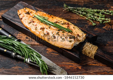 Baked trout fillet on a cutting board. Dark wooden background. Top view Royalty-Free Stock Photo #1846152730