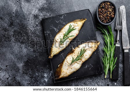 Baked halibut fish steak. Black background. Top view. Copy space