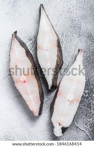 Raw fresh steak fish halibut on the stone table. White background. Top view