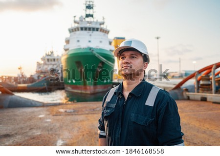 Marine Deck Officer or Chief mate on deck of offshore vessel or ship , wearing PPE personal protective equipment - helmet, coverall. Ship is on background Royalty-Free Stock Photo #1846168558