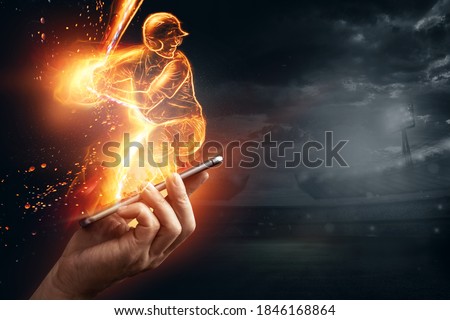 A silhouette, an image of a baseball player with a bat on fire crawls out of a smartphone, a hologram. Online sports concept, betting, American game