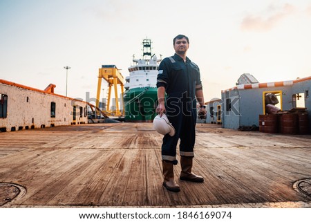 Marine Deck Officer or Chief mate on deck of offshore vessel or ship , wearing PPE personal protective equipment - helmet, coverall. Ship is on background Royalty-Free Stock Photo #1846169074