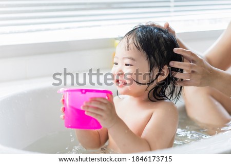 Cute Asian kid toddler having a bath cleaning bathing bath tub with mother, parenthood child hood love and care happy innocent having fun playing with water enjoying life moment white light background