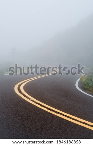 Twisty road into the fog