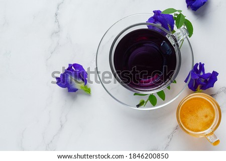 Cup of Butterfly pea flower tea with honey on table