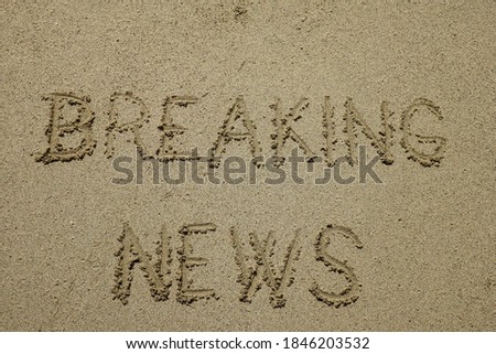 breaking news, sign on the sand beach. word message written on the sand