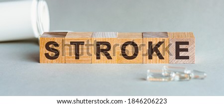 Word Stroke. Stroke text on wooden blocks. In front of a row of cubes are ampoules, in the background - white plastic packaging from tablets, the cubes are located on a gray surface. Concept Image.