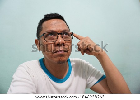 Funny expression of an Asian man stock photo on green bright background. self potrait.