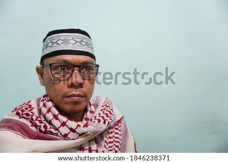 An Asian moeslem man wearing "sorban" stock photo on green bright background. self potrait.