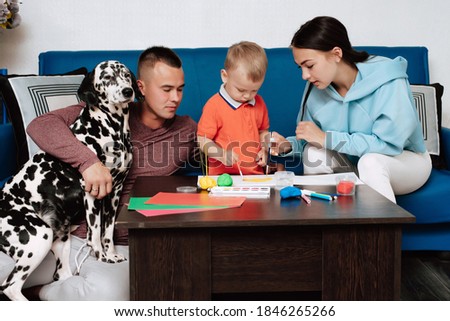 young Caucasian family with a dog do creative work at home, paint and sculpt with plasticine
