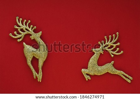 Christmas card concept. Christmas golden toy deers on a red background. Celebration concept