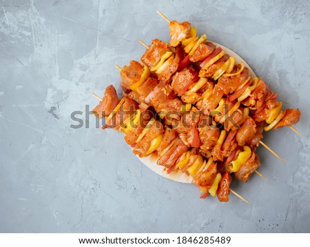 Uncooked marinated and rubbed chiken or turkey shish kebabs on skewers ready for grilling or BBQ. Raw meat in a marinade with spices on a friendly disposable plate. Top view. Copy space. Royalty-Free Stock Photo #1846285489